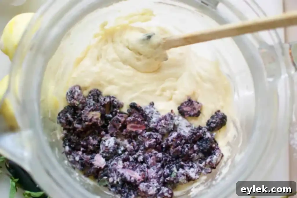 Close-up of muffin batter, showing texture and distribution of blackberries