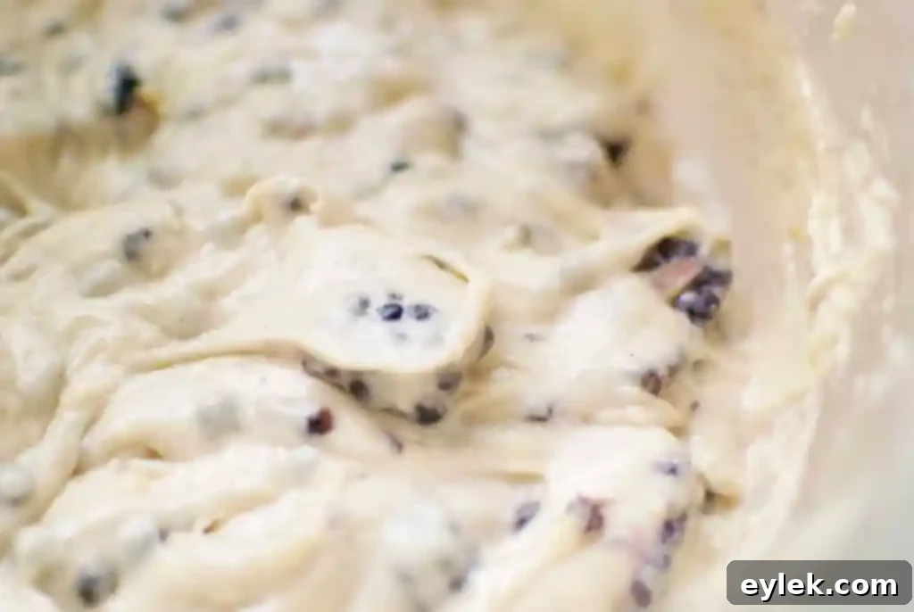 Prepared muffin batter with blackberries and thyme, showcasing its thick consistency