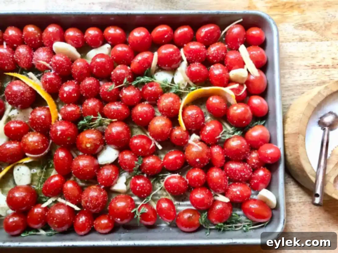 Tomatoes and seasoning tossed on baking sheet