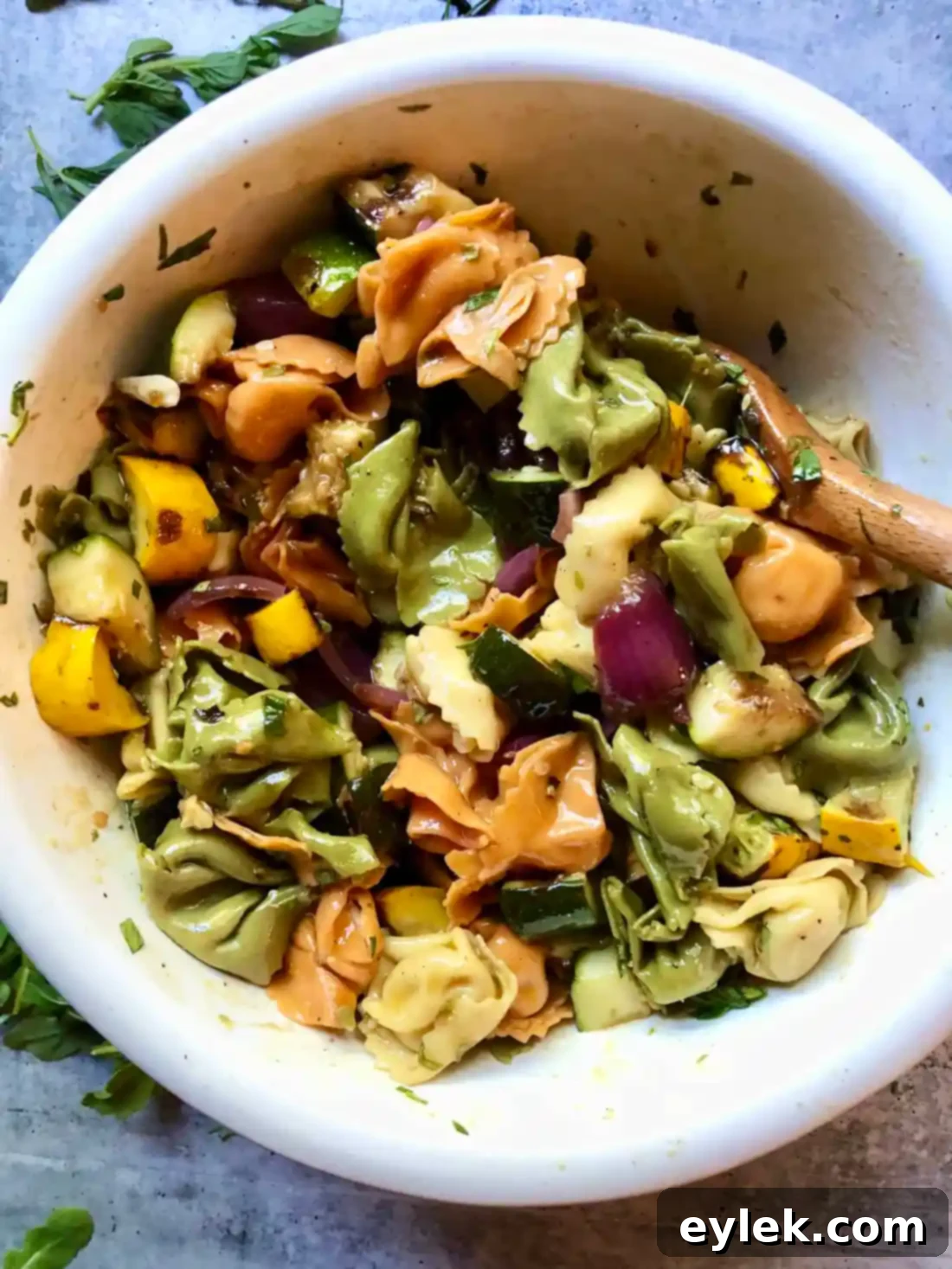Tortelloni salad with grilled vegetables being dressed with vinaigrette