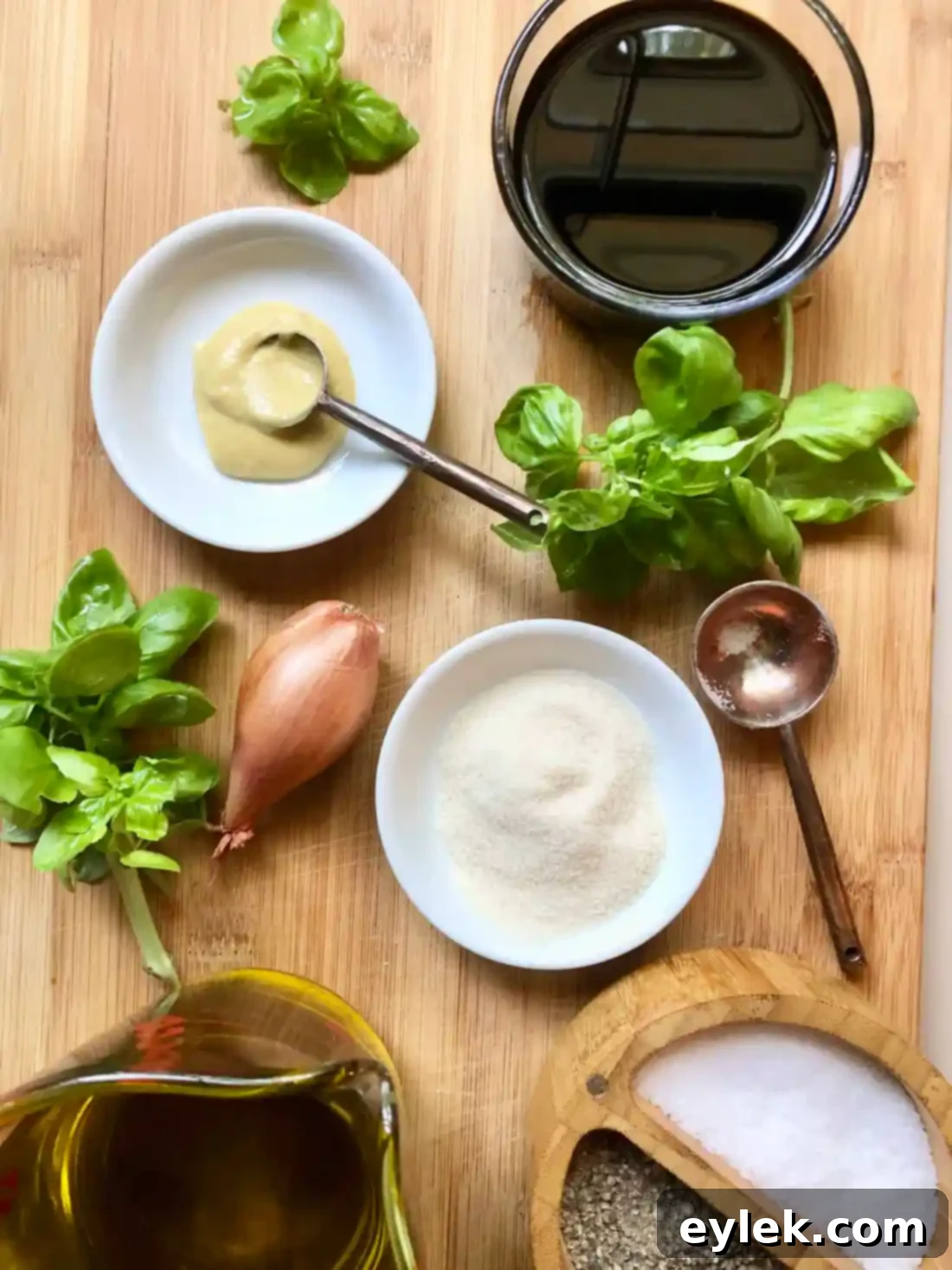 Fresh ingredients for homemade balsamic vinaigrette including olive oil, balsamic vinegar, Dijon mustard, shallot, and basil.