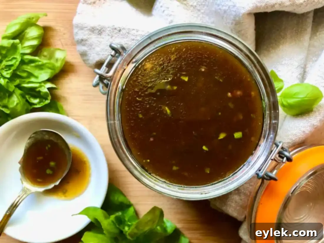 A glass of authentic homemade balsamic vinaigrette with fresh basil leaves.