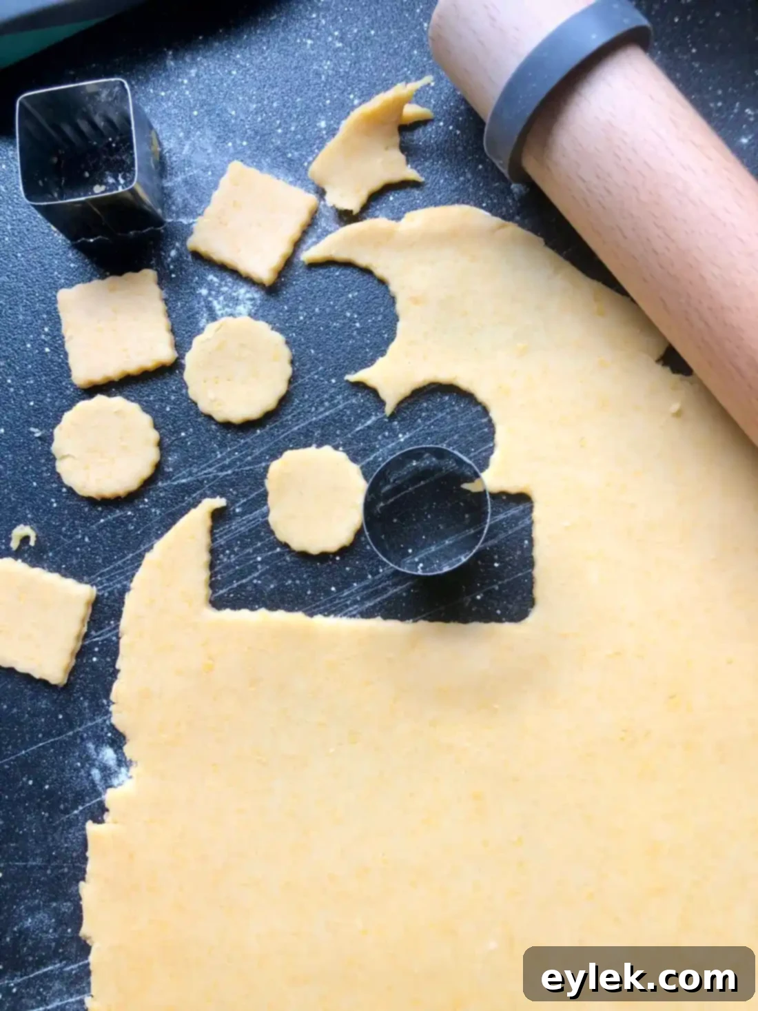 Small square cookie cutter cutting out cheese cracker shapes