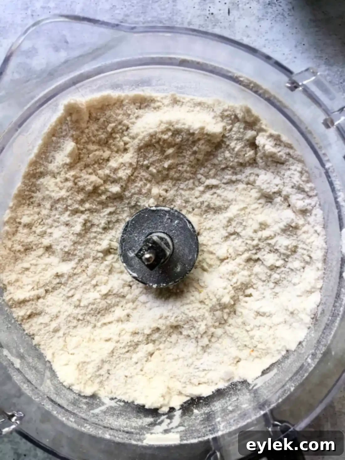Craggy mass of pie dough forming in a food processor