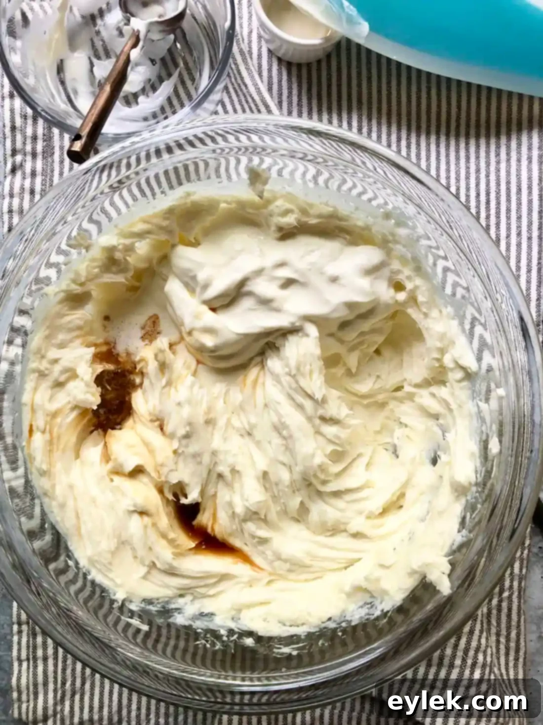 Adding eggs to the creamy cheesecake batter.