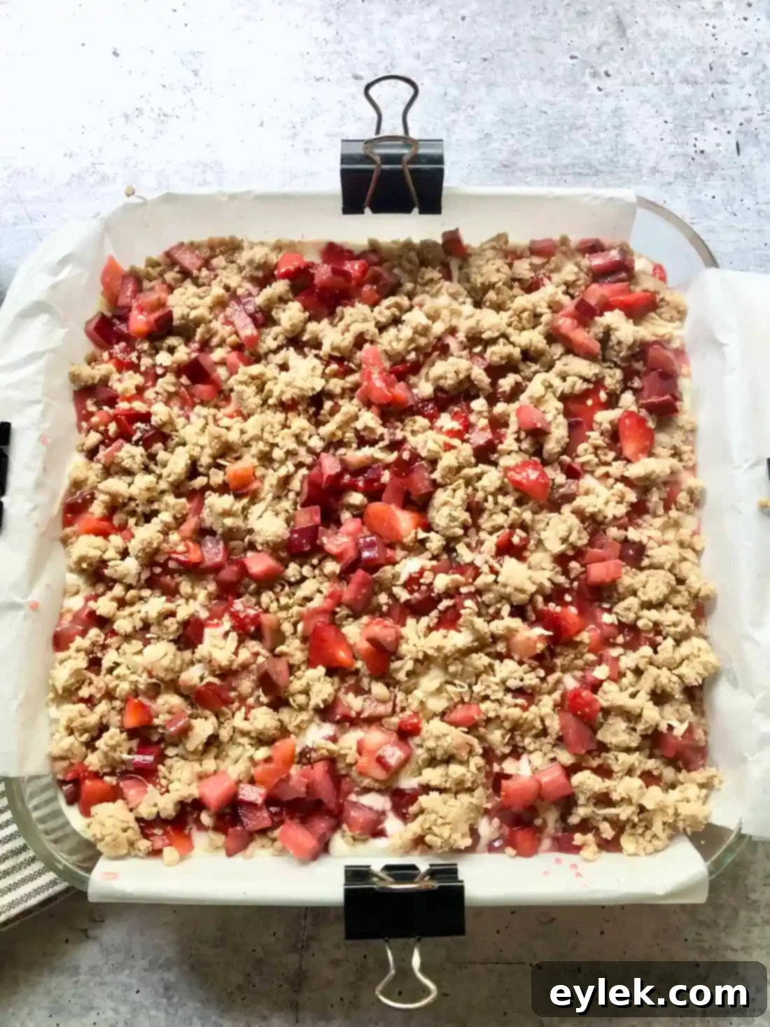 Strawberry Rhubarb Cheesecake Squares baking in the oven, with a golden brown crumble topping.