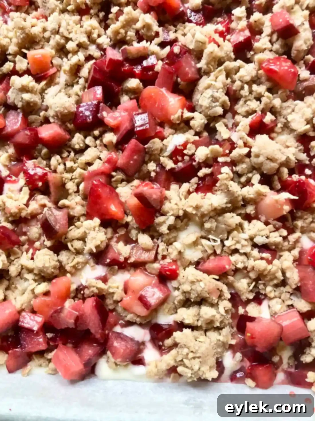 Baked strawberry rhubarb cheesecake squares, fresh from the oven, with a golden-brown crumble top.