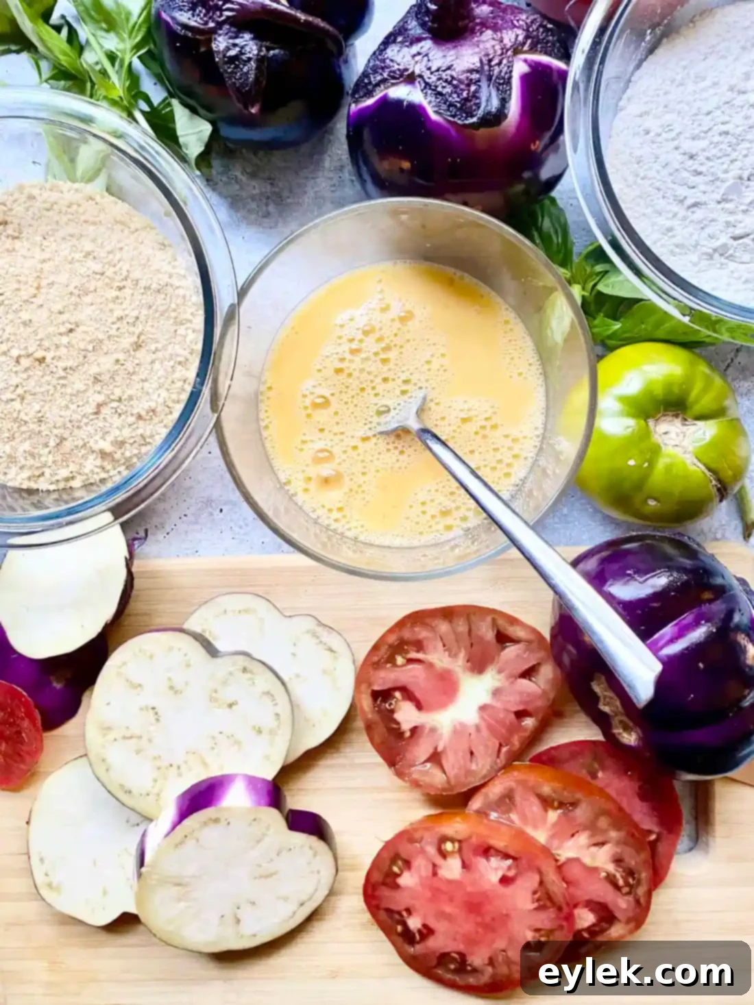 Dredging station with flour, egg, and breadcrumbs for frying eggplant and tomatoes.