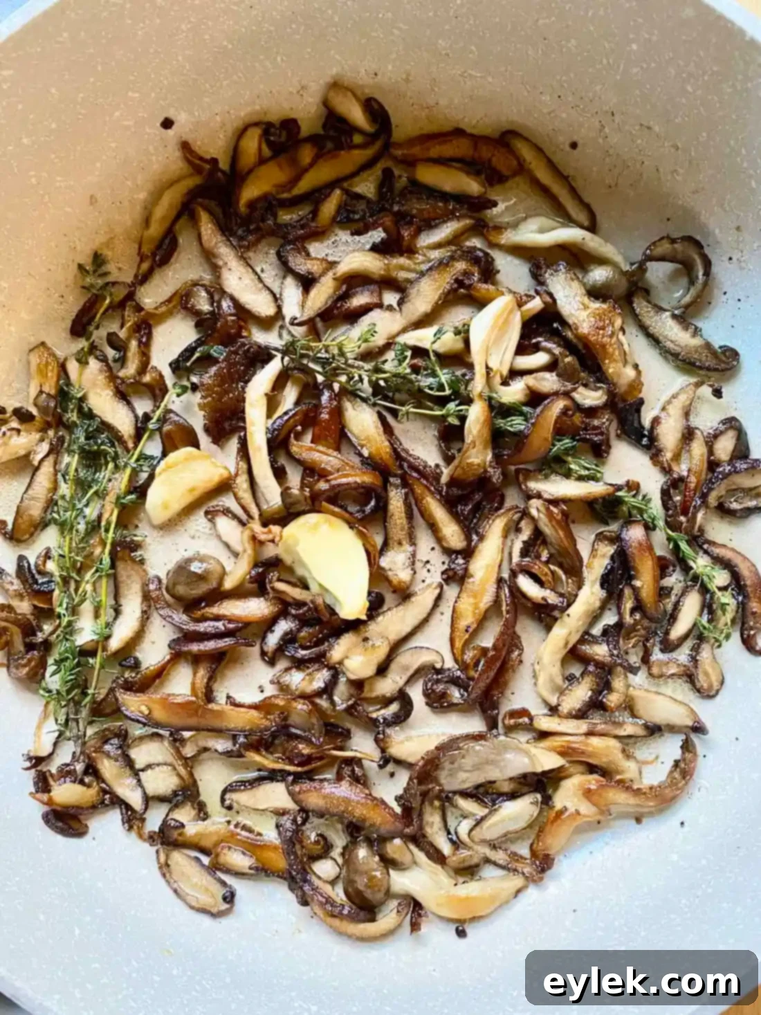 Mushrooms browning in a skillet with thyme, garlic, and foaming butter