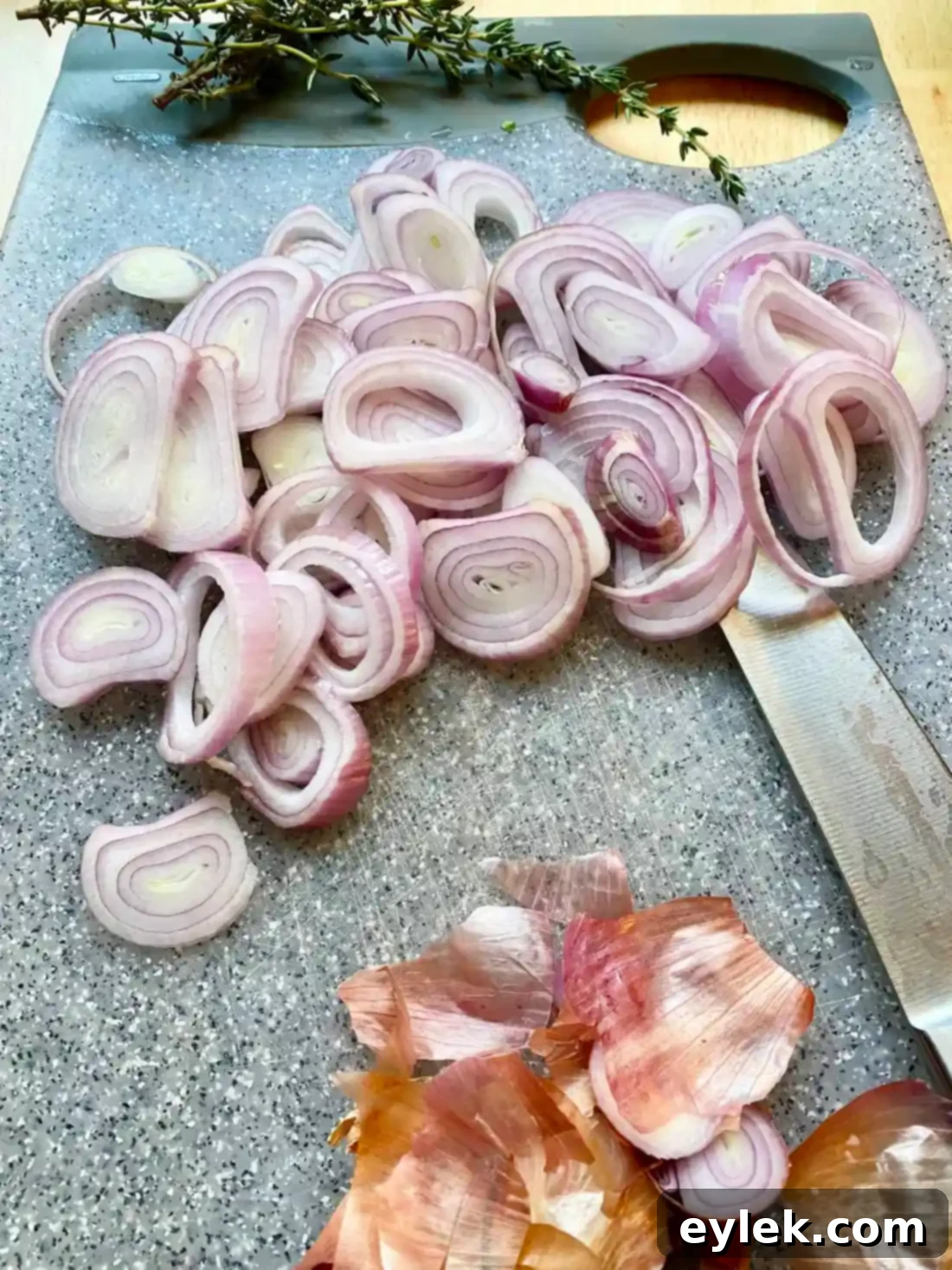 Sliced shallots frying in neutral oil in a small saucepan until golden brown