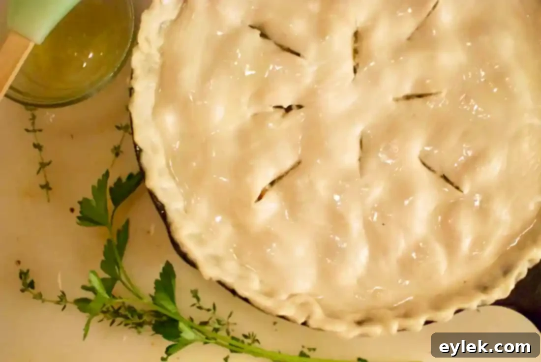 Skillet chicken pot pie topped with pastry crust, ready for the oven