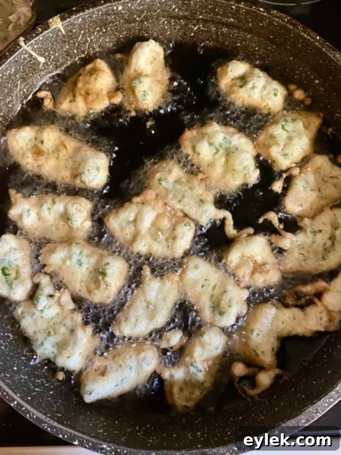 Crispy fried artichoke hearts frying in a pan