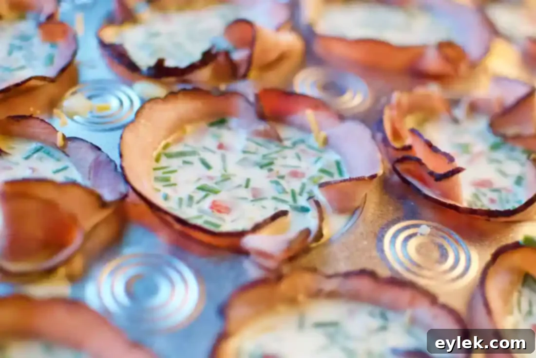Muffin tin with ham cups filled with egg mixture and cheese