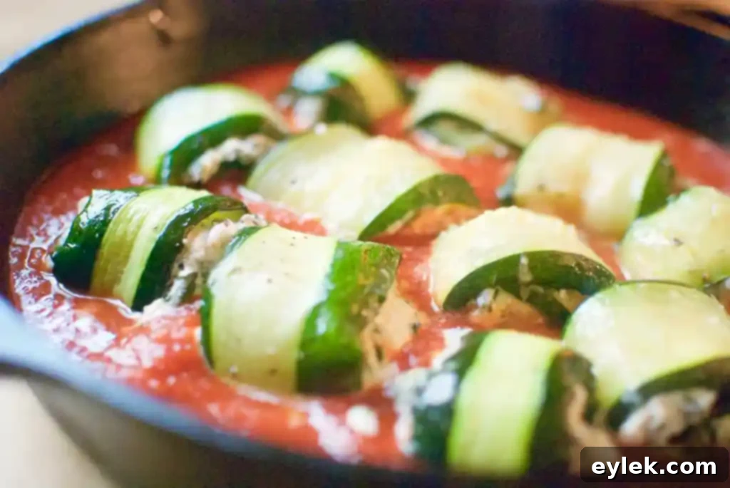 Assembled zucchini involtini in a baking dish with marinara sauce
