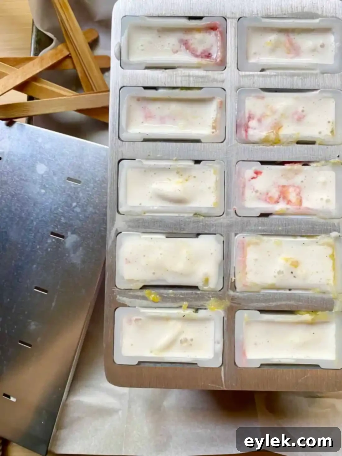 Adding softened vanilla ice cream to popsicle molds