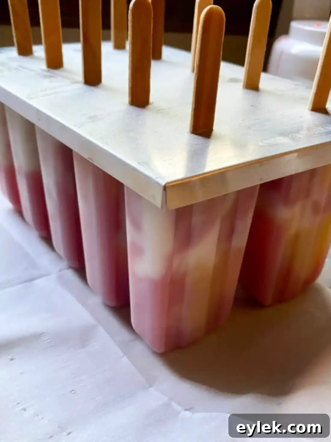 Marbling layers of fruit puree and ice cream in a popsicle mold