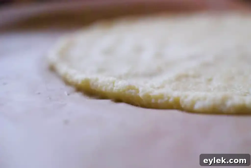 Cauliflower pizza crust mixture being spread out on parchment paper into a circular shape.