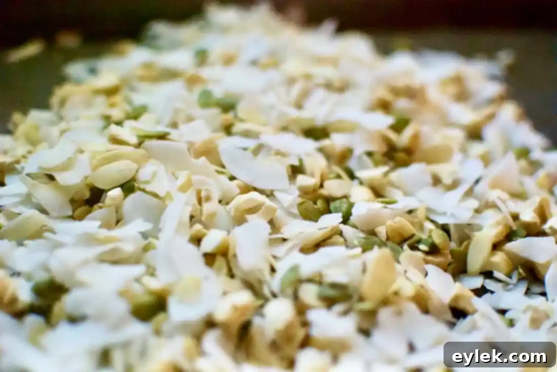 Chopped nuts and coconut flakes on a baking sheet before toasting
