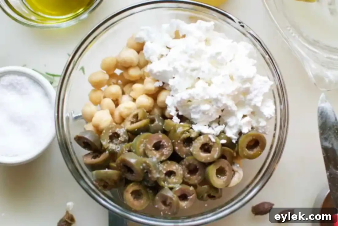 Bowl of fresh chickpea salad with green olives and crumbled feta cheese, dressed and ready