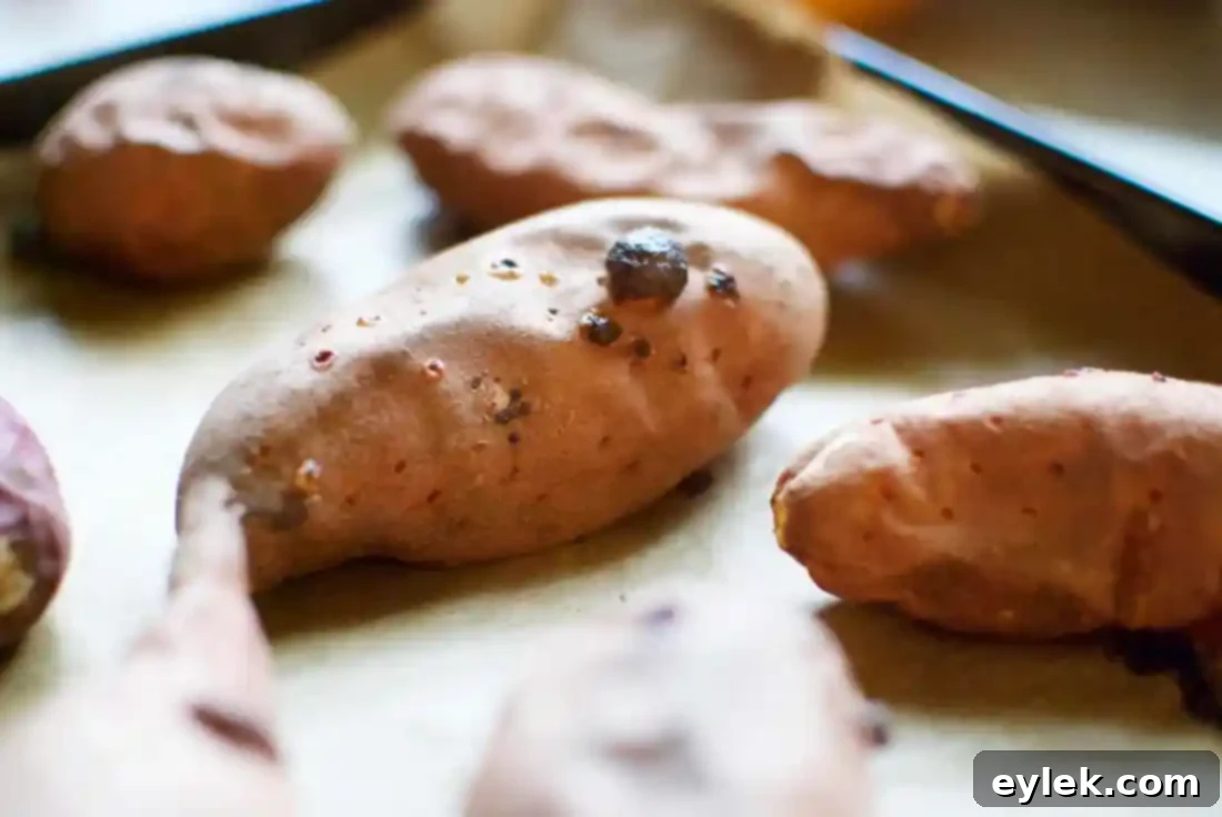 Roasted sweet potatoes being torn open and arranged on a large white serving platter