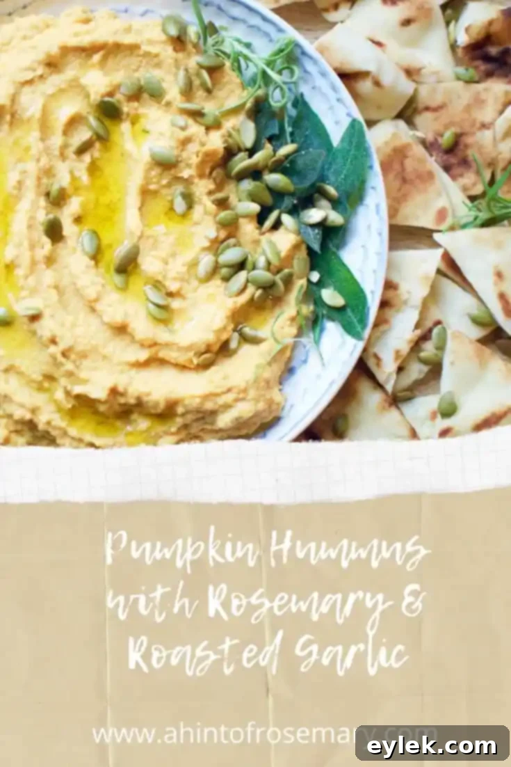Vertical shot of Pumpkin Hummus with Rosemary & Roasted Garlic garnished with fresh herbs