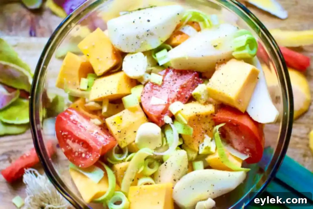 Pears, butternut squash, and other vegetables tossed with olive oil and spices in a bowl