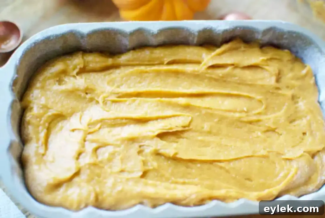 Gluten-free pumpkin bread batter with cream cheese filling, topped and ready for the oven