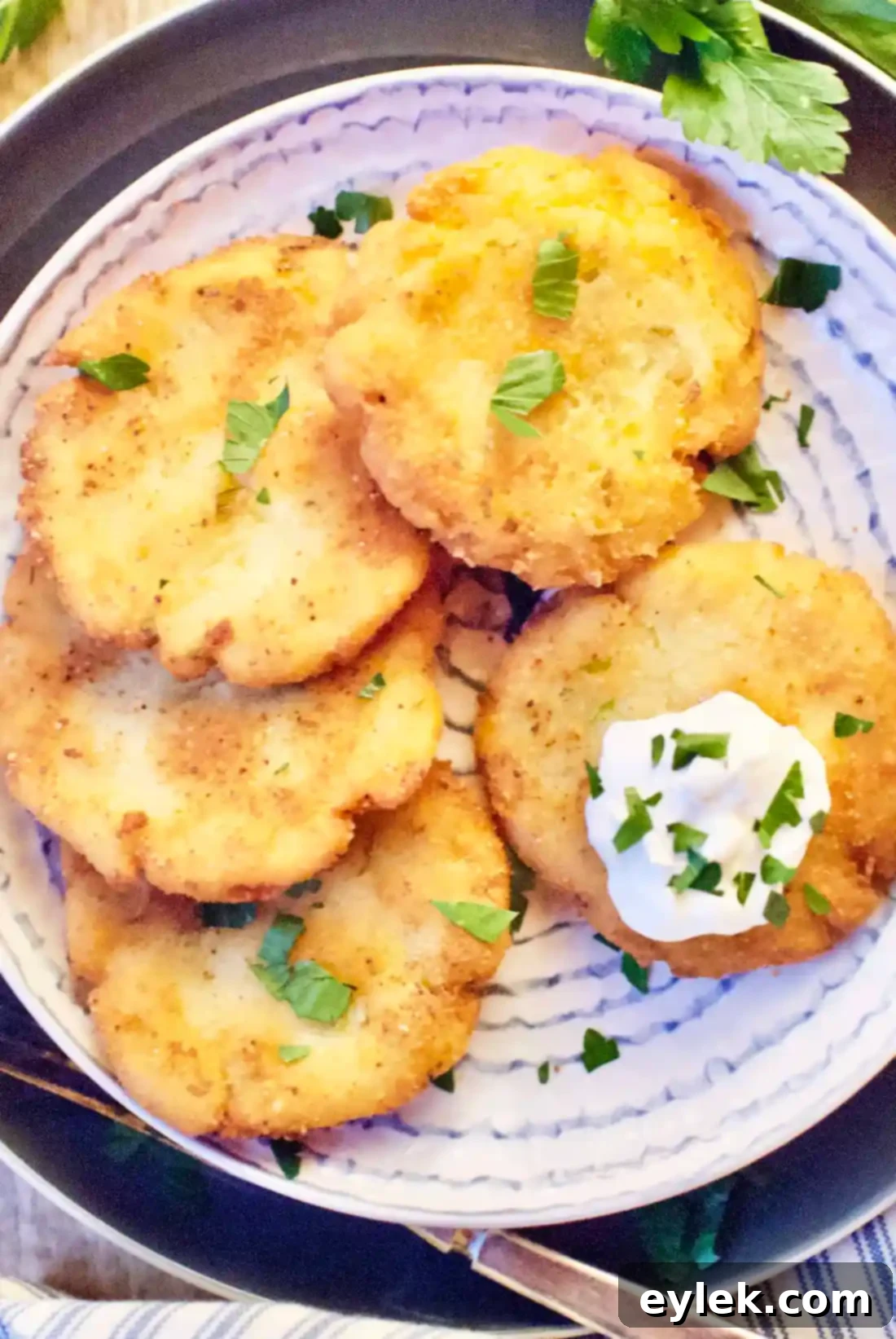 A stack of golden, crispy potato pancakes, some topped with sour cream and chives, inviting a delicious bite.
