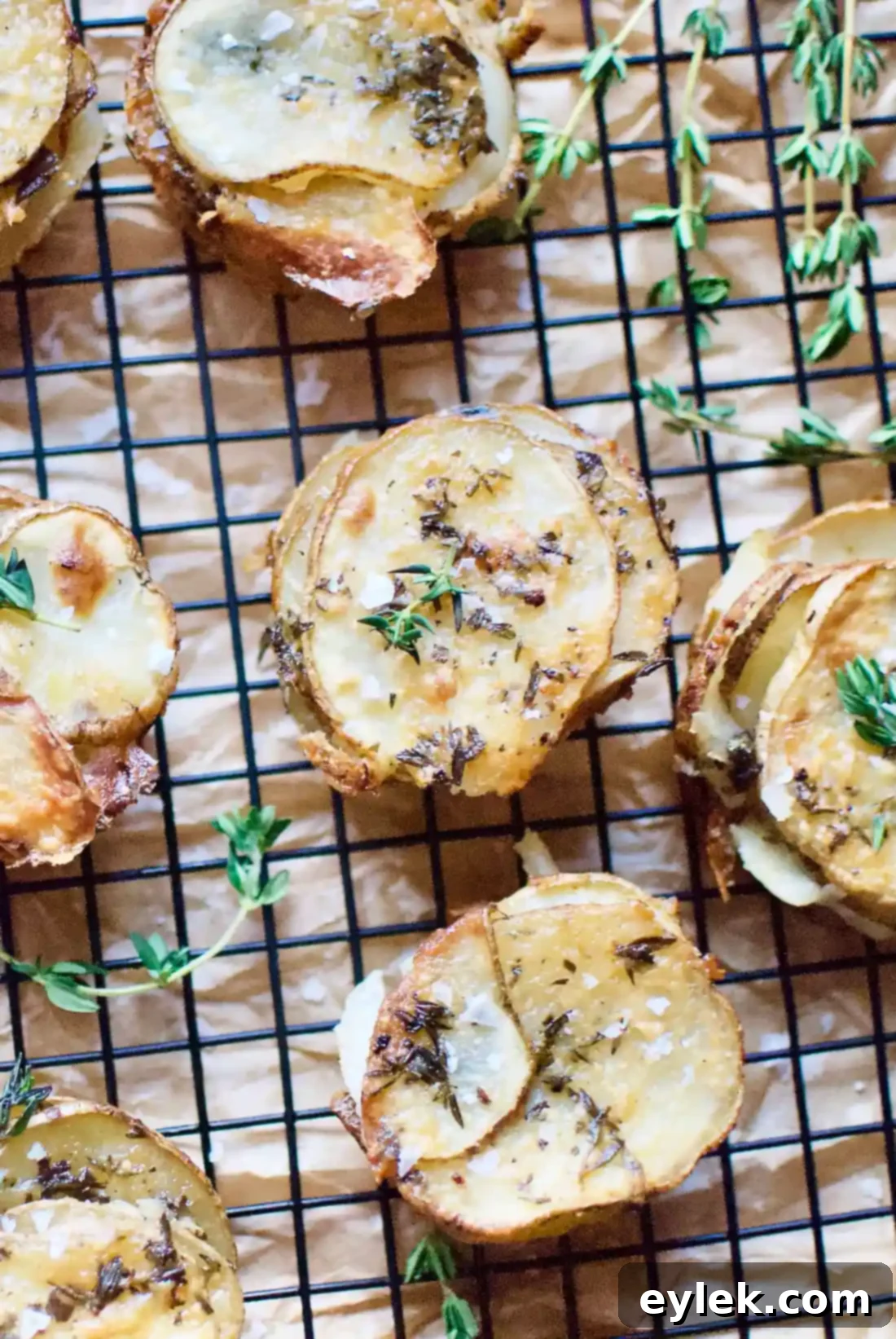 Thinly sliced mini-potatoes are buttered and herbed, then carefully layered with yummy cheese in a muffin tin to produce these crispy Cheesy Potato & Herb Stacks. A Hint of Rosemary #roastedpotatoes #cheesypotatoes #potatostacks #muffintinpotatoes #kidfriendly #glutenfree #ahintofrosemary #side #sides #cheese #muffintintreats