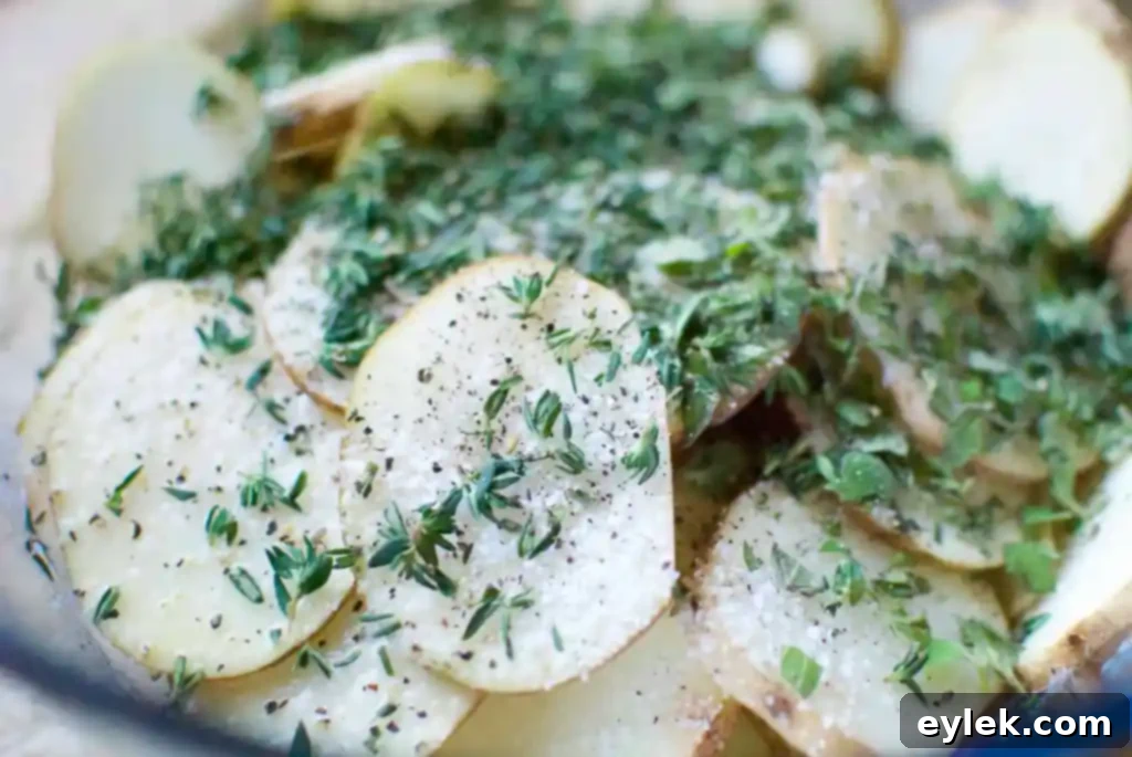 Potatoes being tossed with fresh herbs and melted butter in a bowl.