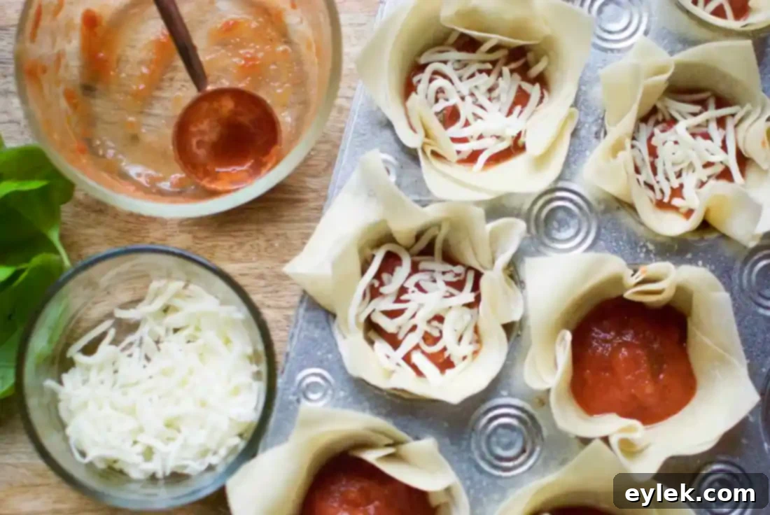 Muffin tin cups filled with marinara, mozzarella, and an uncooked egg, ready for baking.