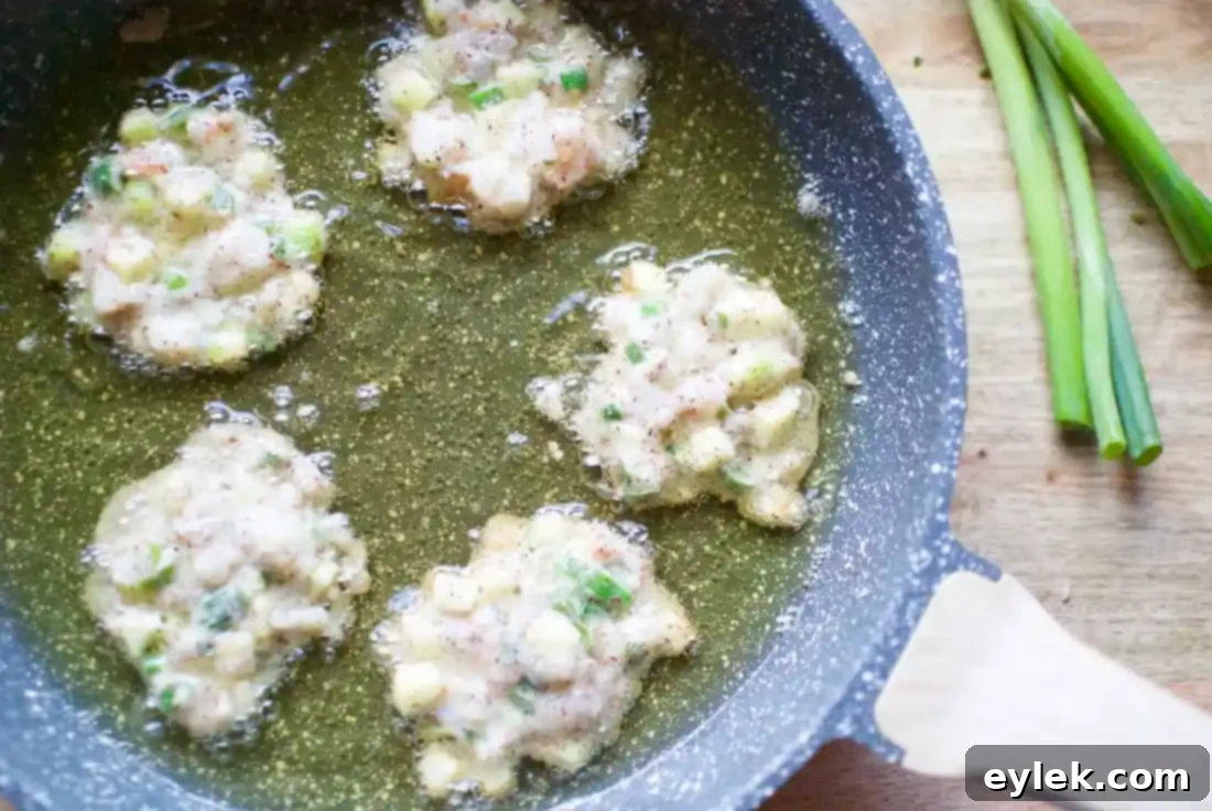 Frying shrimp and zucchini fritters in a skillet