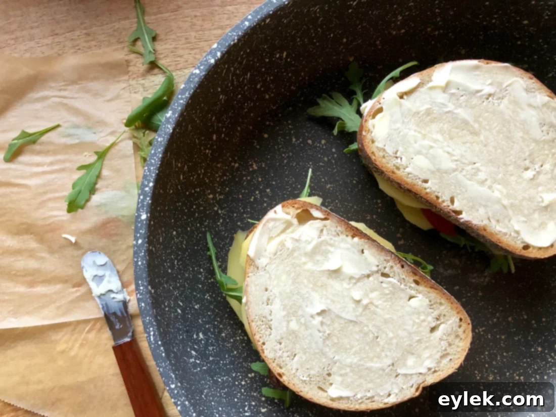 Grilled cheese sandwich cooking in a pan with butter