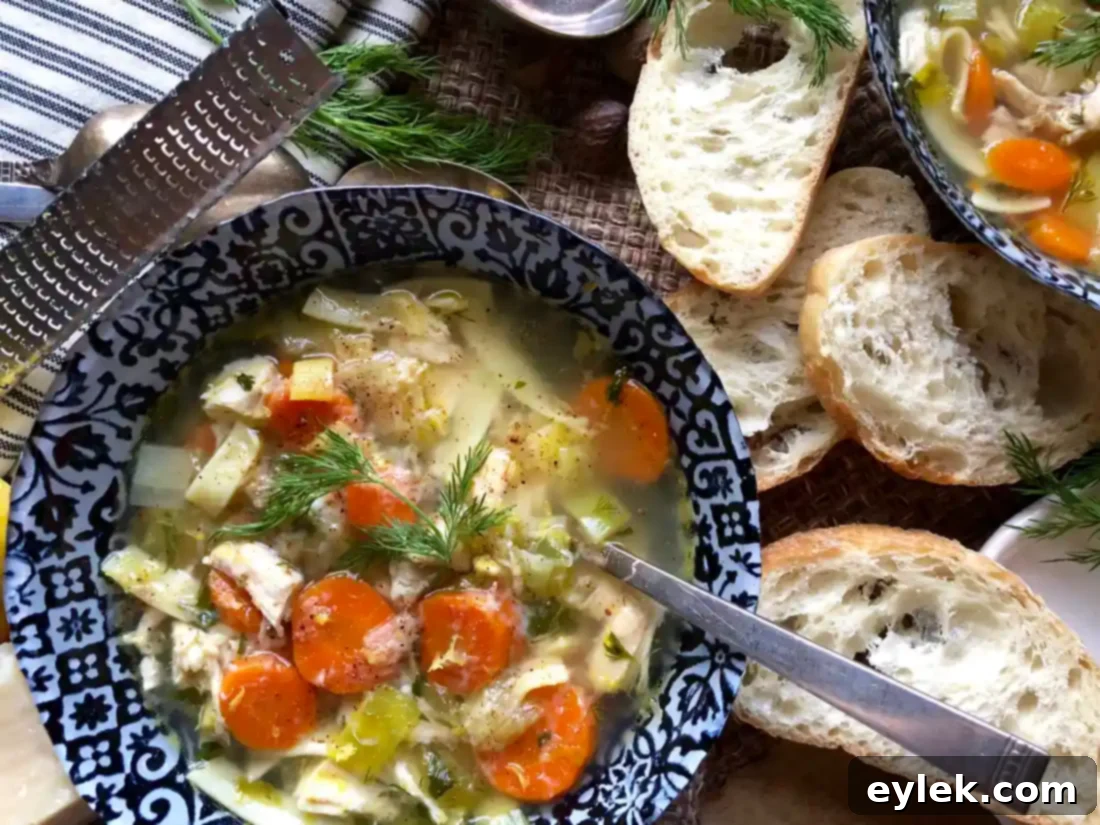 Finished chicken noodle soup in a bowl, garnished with fresh herbs and cheese.