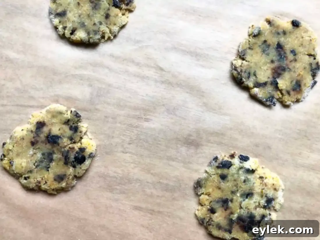 Rolling pin flattening cookie dough between two sheets of parchment paper.