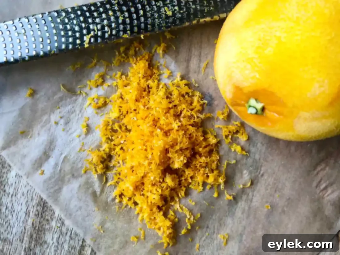 Close-up of freshly grated orange zest and sugar being pinched together.