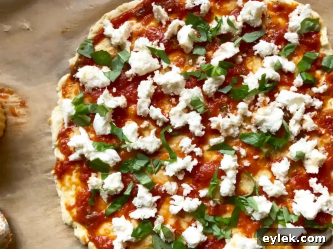 Gluten-free pizza dough spread thinly on parchment paper, ready for sauce and toppings.