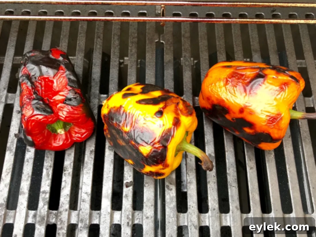 Bell peppers charring on an outdoor grill, showing blistered skin
