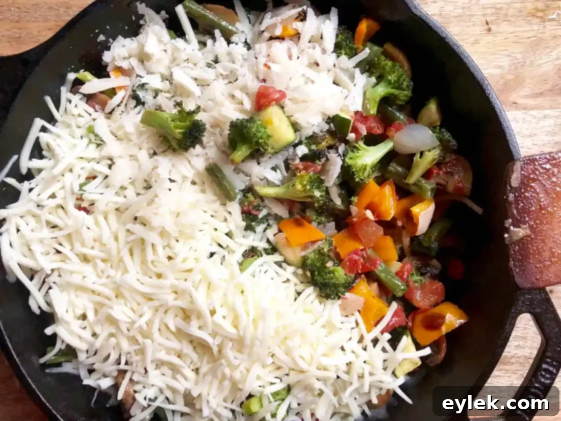 close-up of vegetables and cheese mixed in a skillet before baking