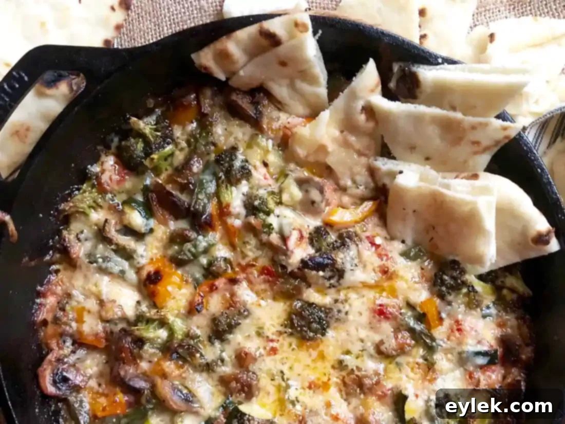 close-up of cheesy roasted ratatouille dip with a dipper, emphasizing its creamy texture