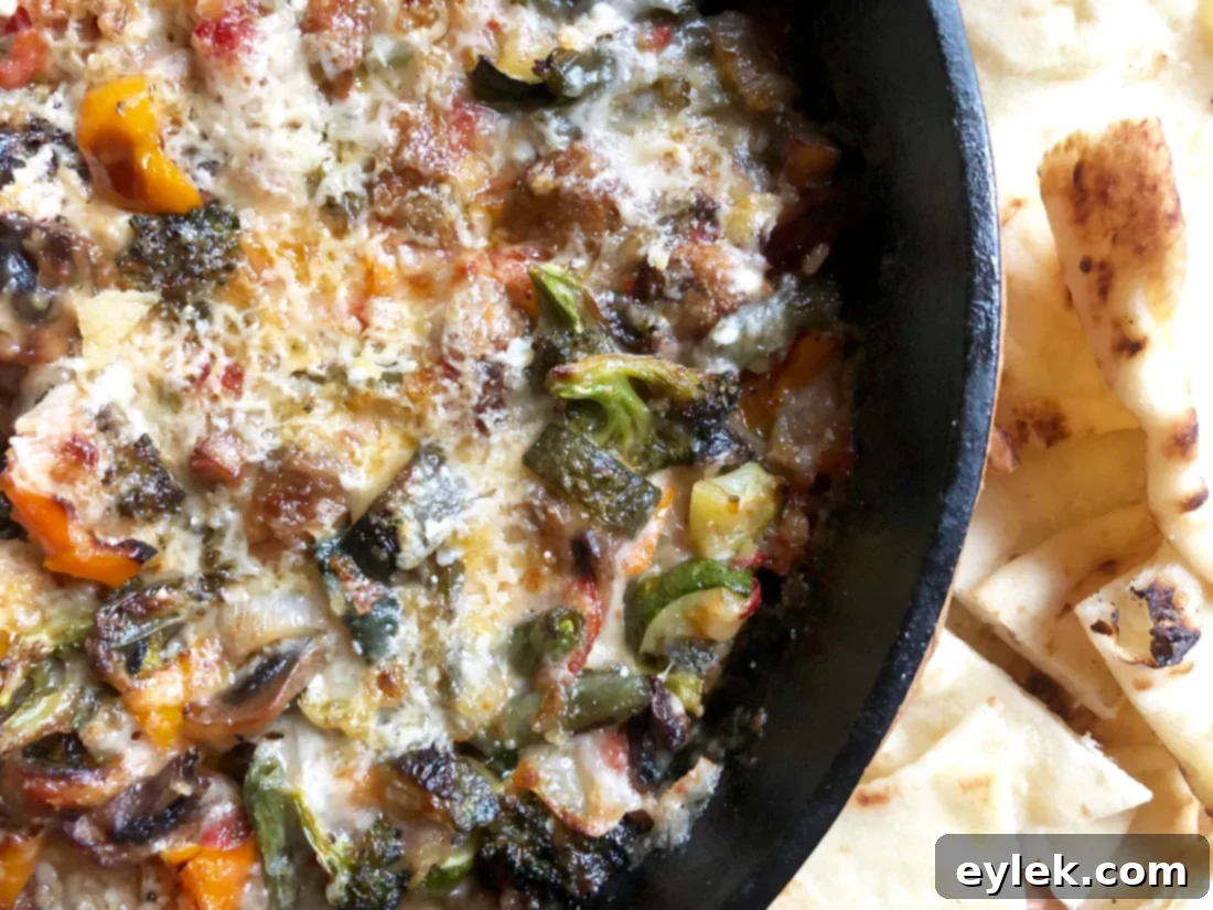 cheesy roasted ratatouille dip in a serving bowl with fresh herbs garnish