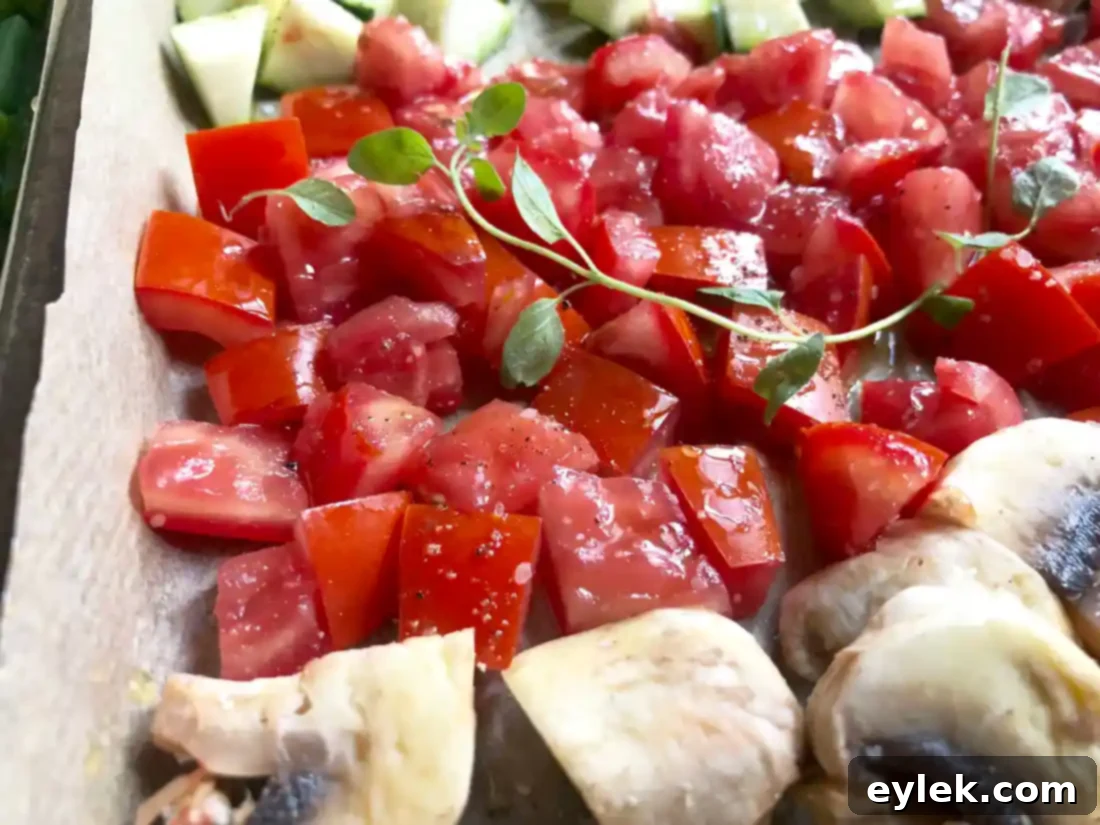 assorted vegetables coated in olive oil and seasonings on a baking sheet
