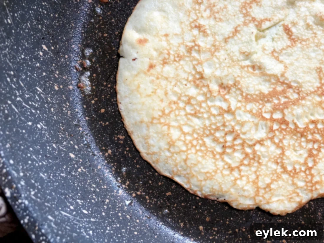 Spatula gently lifting the edge of a cooked low-carb crepe