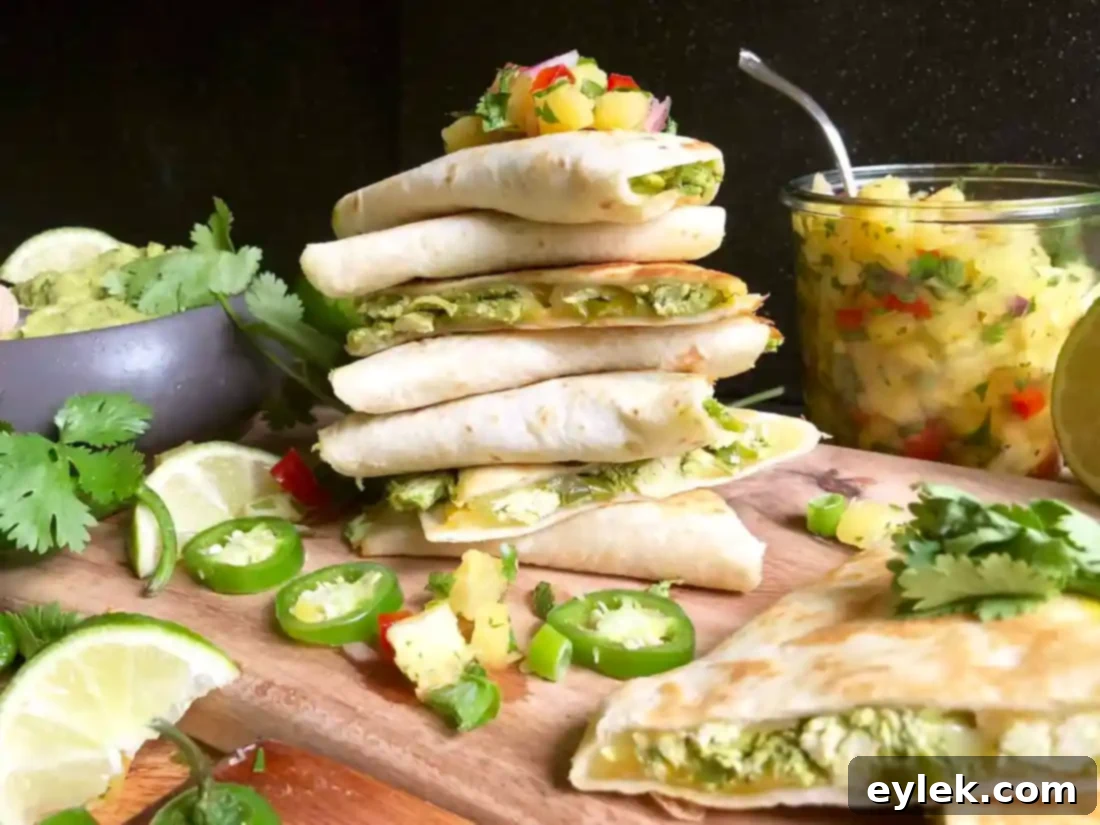 A stack of golden-brown chicken fajita quesadilla wedges, garnished with fresh cilantro and a lime wedge.