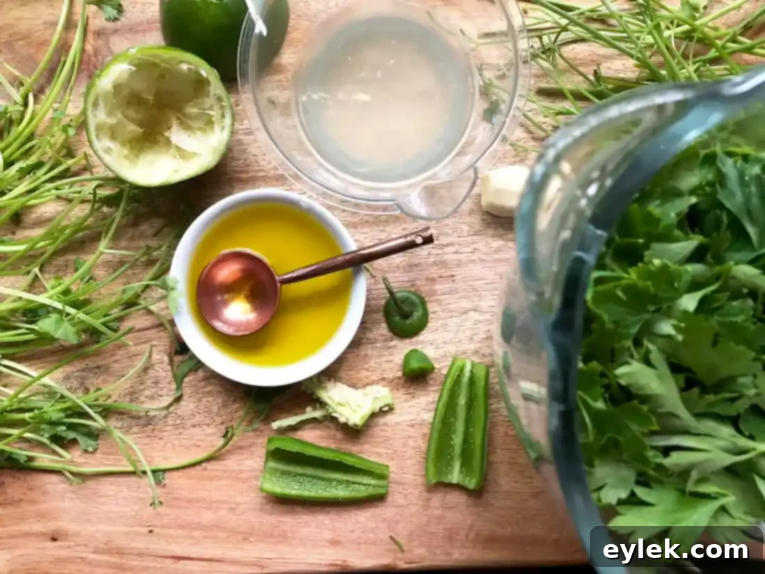 Ingredients for green chile sauce in a blender, including cilantro, parsley, garlic, and jalapeño.