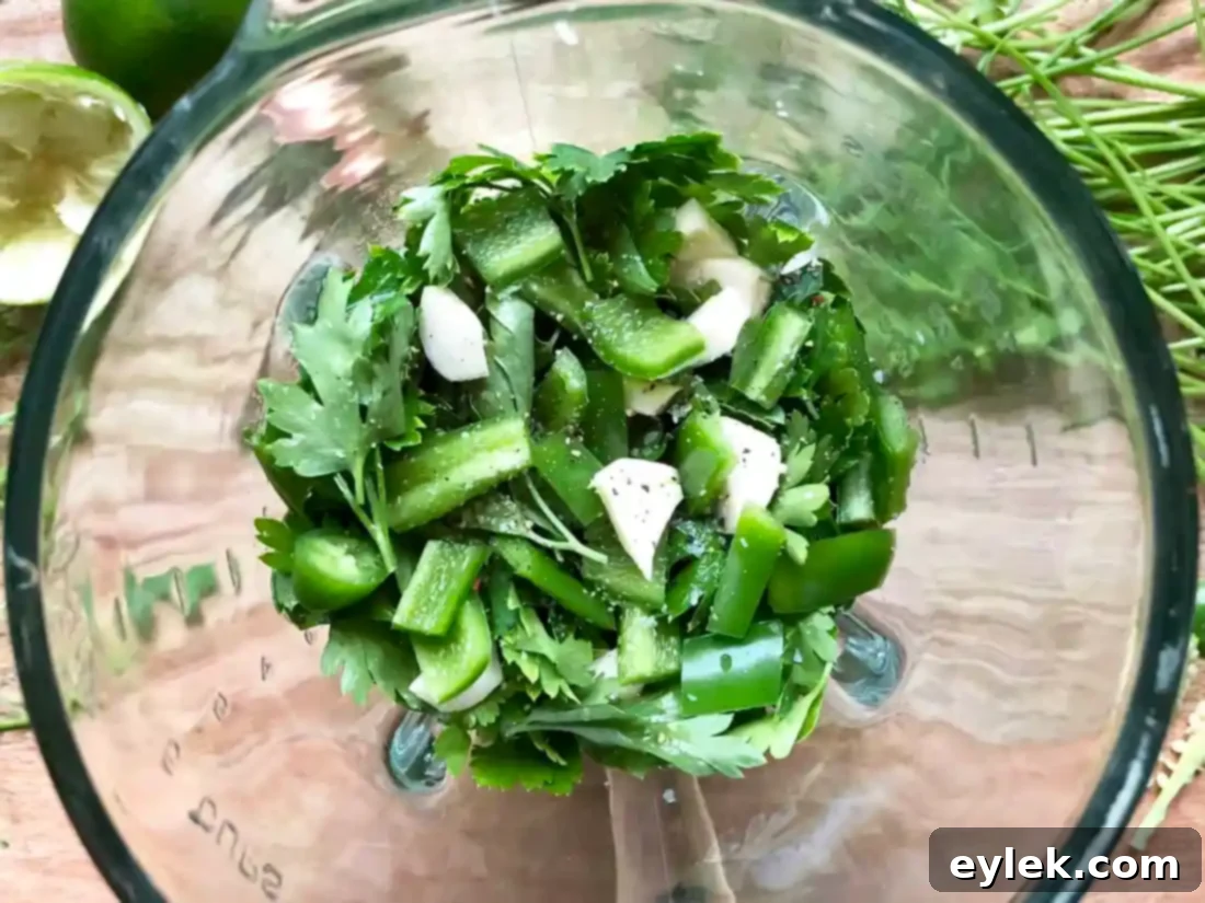 Blender with vibrant green chile sauce being prepared.
