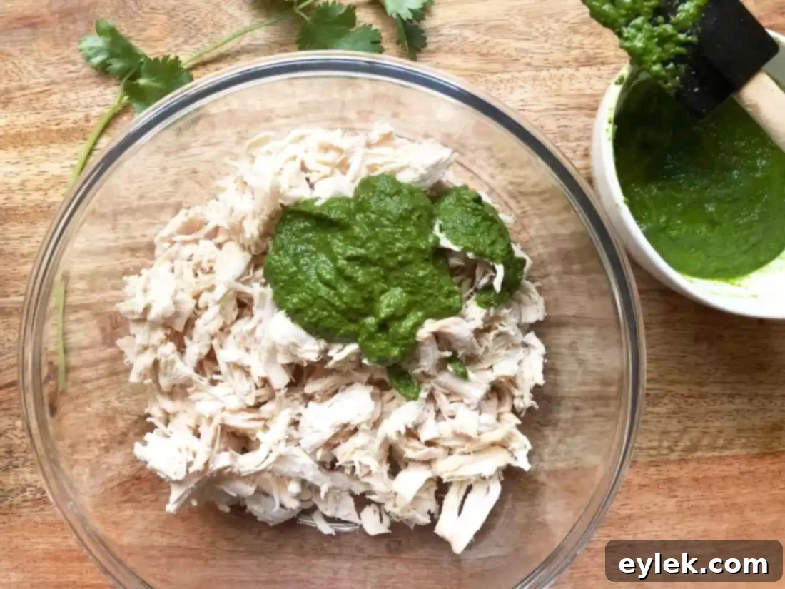 Shredded chicken mixed with green chile sauce in a bowl, ready for quesadillas.