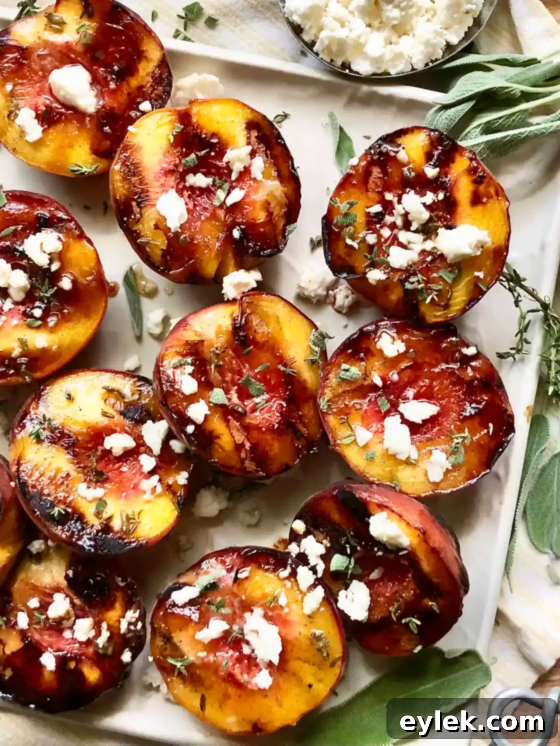 Beautifully plated Grilled Peaches with Honey & Queso Fresco, close-up with fresh herbs