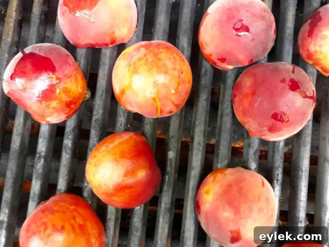 Peach halves being grilled on a BBQ with visible grill marks forming