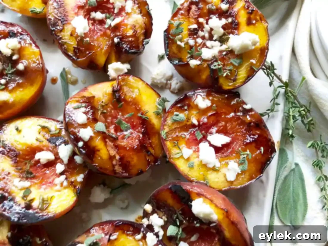 Grilled Peaches with Honey & Queso Fresco served on a white platter, garnished with fresh herbs